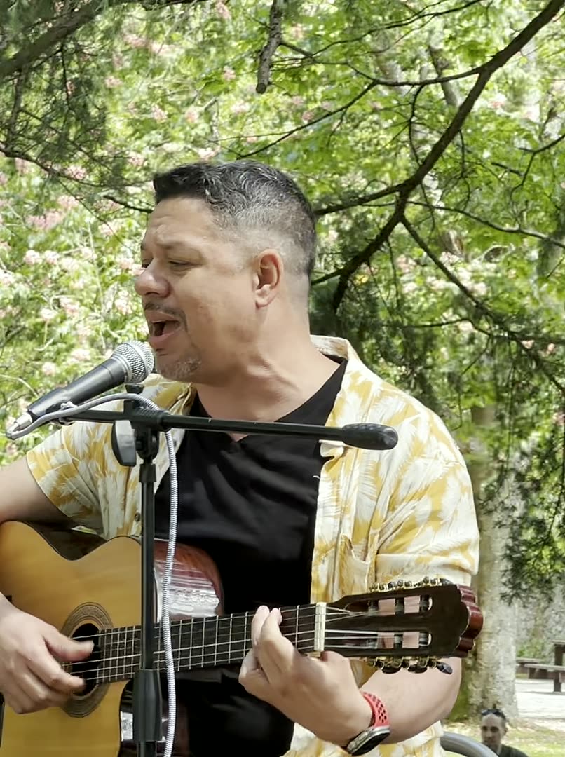 Retrato de Auri Toledo con guitarra acústica, luz cálida sobre fondo oscuro