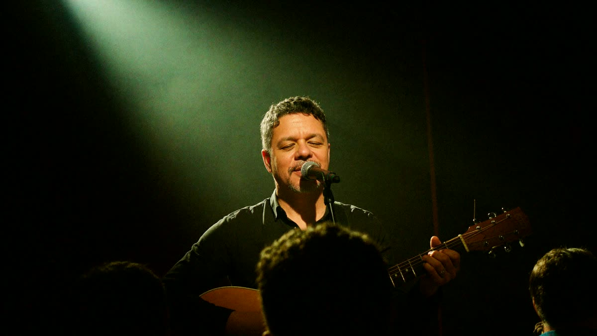 Auri Toledo cantando bajo un foco cálido en el escenario de una sala